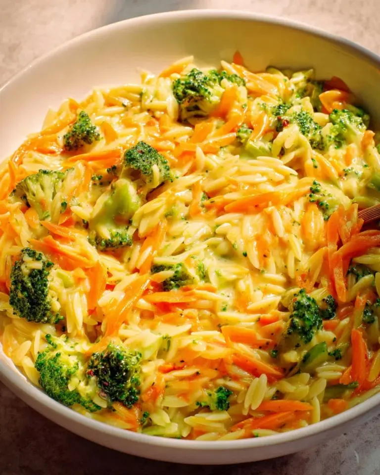 Creamy broccoli cheddar orzo dish served in a bowl with fresh herbs