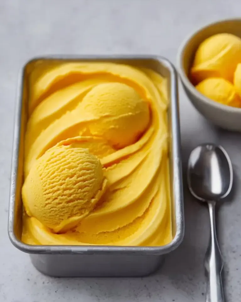Delicious bowl of homemade mango ice cream with fresh mango slices on top.