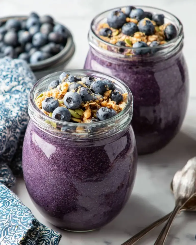A bowl of blueberry chia pudding topped with fresh berries and nuts