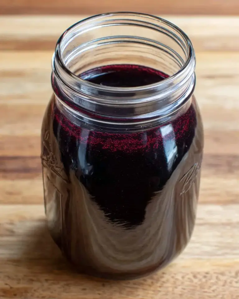 Homemade blueberry simple syrup served in a glass jar on a wooden table